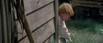 Movie still from “Tom Sawyer” (1973), directed by Don Taylor – A young boy leaning against a wooden fence; Medium shot, High angle