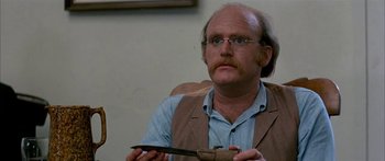 Movie still from “Tom Sawyer” (1973), directed by Don Taylor – An older man with glasses holding a knife in his hand; Close Up shot, High angle