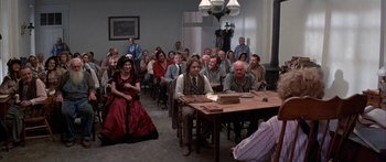 Movie still from “Tom Sawyer” (1973), directed by Don Taylor – A group of people sitting around a table in a room; Wide shot, High angle