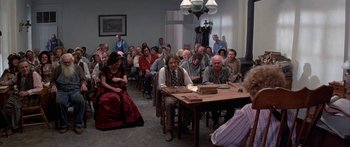 Movie still from “Tom Sawyer” (1973), directed by Don Taylor – A group of people sitting around a table in a room; Wide shot, High angle
