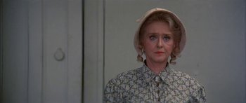 Movie still from “Tom Sawyer” (1973), directed by Don Taylor – An older woman wearing a hat in a room; Close Up shot, Over the shoulder angle