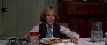 Movie still from “Tom Sawyer” (1973), directed by Don Taylor – A young man sitting at a table with a plate of food; Close Up shot, Over the shoulder angle