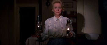 Movie still from “Tom Sawyer” (1973), directed by Don Taylor – A woman holding two oil lamps while standing in front of a fireplace; Medium shot, Low angle