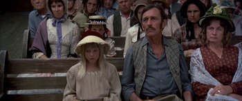 Movie still from “Tom Sawyer” (1973), directed by Don Taylor – A man and a little girl sitting next to each other in front of a crowd; Medium shot, High angle