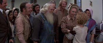 Movie still from “Tom Sawyer” (1973), directed by Don Taylor – An old man with long white beard standing in front of a group of people; Medium shot, High angle