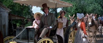 Movie still from “Tom Sawyer” (1973), directed by Don Taylor – A man and two women are riding in a horse drawn carriage; Wide shot, High angle