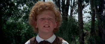 Movie still from “Tom Sawyer” (1973), directed by Don Taylor – A young boy with curly blonde hair wearing a vest and bow tie; Close Up shot, Low angle