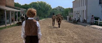 Movie still from “Tom Sawyer” (1973), directed by Don Taylor – A man leading a horse down a dirt road; Wide shot, Over the shoulder angle