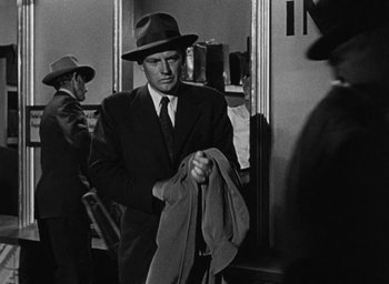 Movie still from “Too Late for Tears” (1949), directed by Byron Haskin – A black and white photo of a man in a suit and hat holding a jacket; Medium shot, Over the shoulder angle