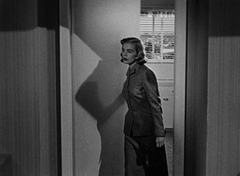 Movie still from “Too Late for Tears” (1949), directed by Byron Haskin – A black and white photo of a woman standing in front of a window; Medium shot, Over the shoulder angle