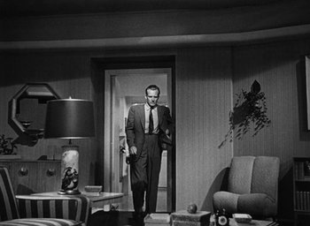 Movie still from “Too Late for Tears” (1949), directed by Byron Haskin – A black and white photo of a man in a suit and tie; Wide shot, Low angle