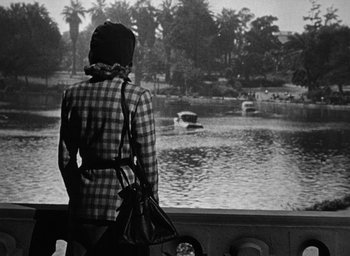 Movie still from “Too Late for Tears” (1949), directed by Byron Haskin – A woman standing on a bridge looking out over a lake; Wide shot, Over the shoulder angle