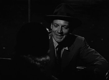 Movie still from “Too Late for Tears” (1949), directed by Byron Haskin – A black and white photo of a man in a suit and a hat; Close Up shot, Over the shoulder angle