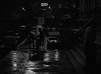 Movie still from “Too Late for Tears” (1949), directed by Byron Haskin – A person sitting at a table in a dark room; Wide shot, High angle