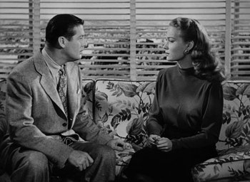 Movie still from “Too Late for Tears” (1949), directed by Byron Haskin – A man and a woman sitting on a couch talking to each other; Medium shot, Over the shoulder angle