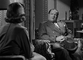Movie still from “Too Late for Tears” (1949), directed by Byron Haskin – An older man sitting in front of a woman in a chair; Medium shot, Over the shoulder angle