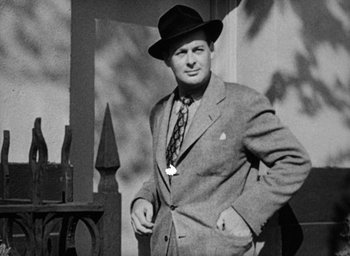Movie still from “Too Late for Tears” (1949), directed by Byron Haskin – An old photo of a man in a suit and hat; Medium shot, Low angle