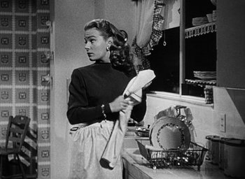Movie still from “Too Late for Tears” (1949), directed by Byron Haskin – A black and white photo of a woman holding a towel; Medium shot, Low angle