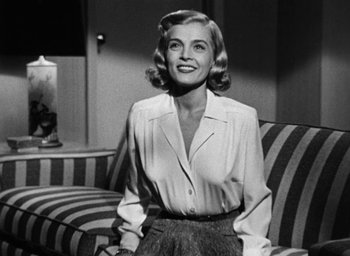 Movie still from “Too Late for Tears” (1949), directed by Byron Haskin – A black and white photo of a woman sitting on a couch; Medium shot, Low angle