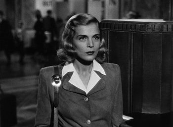 Movie still from “Too Late for Tears” (1949), directed by Byron Haskin – An old black and white photo of a woman holding a wrench; Medium shot, Low angle