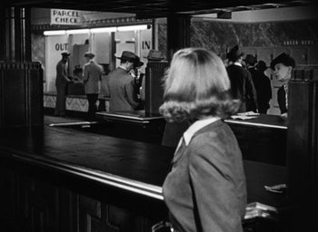 Movie still from “Too Late for Tears” (1949), directed by Byron Haskin – A woman standing in front of a counter in front of other people; Wide shot, Over the shoulder angle