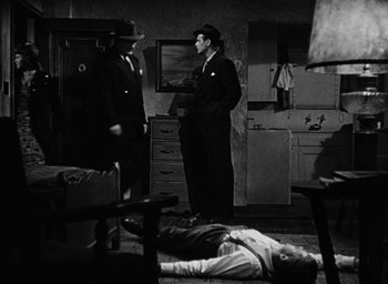 Movie still from “Too Late for Tears” (1949), directed by Byron Haskin – Two men standing in a room next to a dead body; Wide shot, High angle