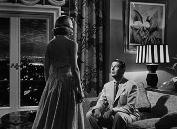 Movie still from “Too Late for Tears” (1949), directed by Byron Haskin – A man and a woman sitting on a couch in a living room; Medium shot, Low angle