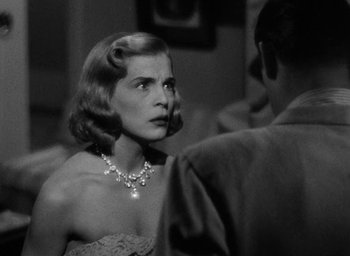 Movie still from “Too Late for Tears” (1949), directed by Byron Haskin – A woman in a strapless dress talking to a man in a suit; Close Up shot, Over the shoulder angle