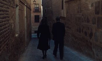 Movie still from “Tristana” (1970), directed by Luis Buñuel – A man and a woman walking down a narrow alley way; Wide shot, High angle