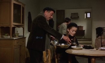 Movie still from “Tristana” (1970), directed by Luis Buñuel – A man and a woman sitting at a dinner table; Medium shot, High angle