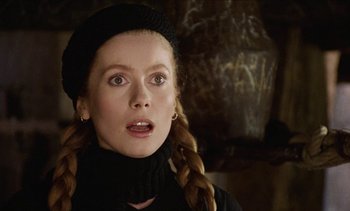 Movie still from “Tristana” (1970), directed by Luis Buñuel – A woman with long blonde plaited hair wearing a black hat; Close Up shot, Low angle