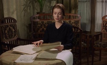 Movie still from “Tristana” (1970), directed by Luis Buñuel – A woman sitting at a table with papers in front of her; Medium shot, High angle