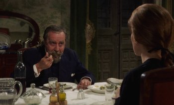 Movie still from “Tristana” (1970), directed by Luis Buñuel – An older man and a young woman are sitting at a dinner table; Medium shot, Over the shoulder angle