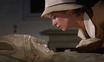 Movie still from “Tristana” (1970), directed by Luis Buñuel – A woman wearing a hat looking at a statue of a head; Close Up shot, Low angle