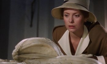 Movie still from “Tristana” (1970), directed by Luis Buñuel – A woman wearing a hat looking at something in a basket; Close Up shot, Over the shoulder angle