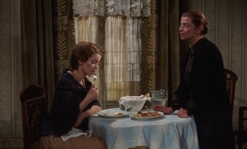 Movie still from “Tristana” (1970), directed by Luis Buñuel – A man and a woman sitting at a dinner table; Medium shot, High angle