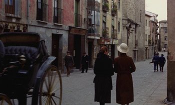 Movie still from “Tristana” (1970), directed by Luis Buñuel – Two women are walking down the street with a horse drawn carriage in the background; Extreme Wide shot, High angle
