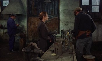Movie still from “Tristana” (1970), directed by Luis Buñuel – A man and a woman working in a workshop; Medium shot, High angle
