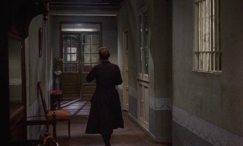 Movie still from “Tristana” (1970), directed by Luis Buñuel – A woman walking down the hall way of a house; Wide shot, High angle