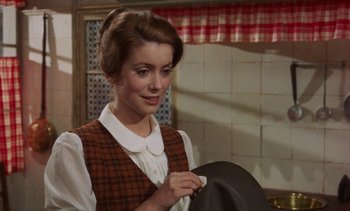 Movie still from “Tristana” (1970), directed by Luis Buñuel – A woman in a plaid vest holding a hat; Close Up shot, Over the shoulder angle