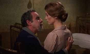 Movie still from “Tristana” (1970), directed by Luis Buñuel – An older man and a young woman embracing each other; Medium shot, Over the shoulder angle