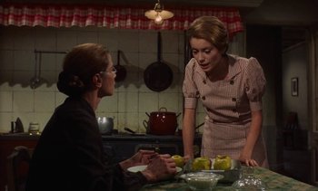 Movie still from “Tristana” (1970), directed by Luis Buñuel – Two women are talking in the kitchen; Medium shot, Over the shoulder angle
