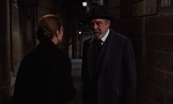 Movie still from “Tristana” (1970), directed by Luis Buñuel – An older man in a black suit and a woman in a black suit; Medium shot, Over the shoulder angle