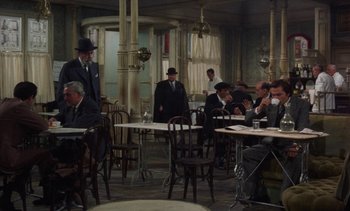 Movie still from “Tristana” (1970), directed by Luis Buñuel – A group of people sitting at tables in a room; Wide shot, High angle