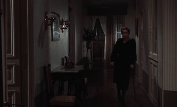Movie still from “Tristana” (1970), directed by Luis Buñuel – An older woman walking down the hall of a house; Wide shot, High angle