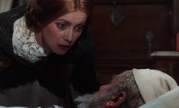Movie still from “Tristana” (1970), directed by Luis Buñuel – A woman looking over a man's shoulder in a dark room; Close Up shot, Over the shoulder angle