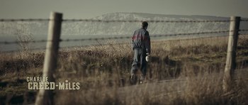 Movie still from “Wild Bill” (2011), directed by Dexter Fletcher – A man walking down a road holding a frisbee in his hand; Wide shot, Low angle