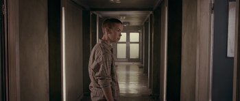 Movie still from “Wild Bill” (2011), directed by Dexter Fletcher – A young man standing in a hallway looking at the camera; Medium shot, Over the shoulder angle