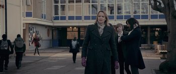 Movie still from “Wild Bill” (2011), directed by Dexter Fletcher – A woman is walking down the street in a black coat; Medium shot, Over the shoulder angle