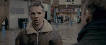 Movie still from “Wild Bill” (2011), directed by Dexter Fletcher – A person wearing a jacket on a city street; Close Up shot, Over the shoulder angle